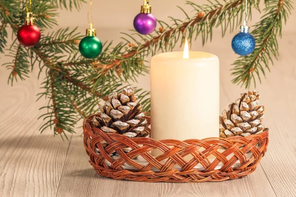 Brinnande ljus, kottar och naturliga fir trädgrenar med julstämning — Stockfoto