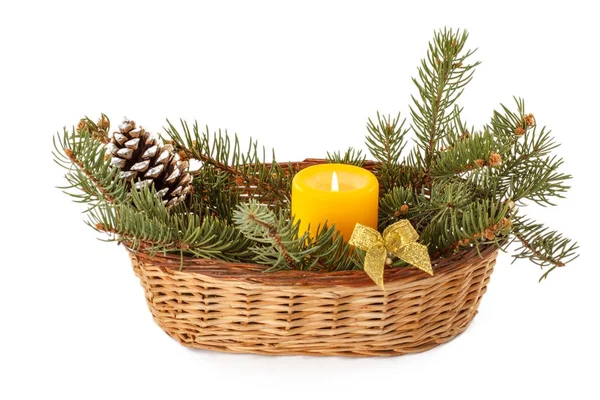 Burning candle, cone and natural fir tree branches in wicker bas — Stock Photo, Image