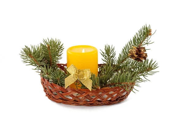 Burning candle, cone and natural fir tree branches in wicker bas — Stock Photo, Image