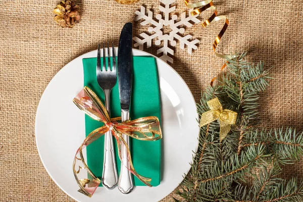 Knife and fork on green napkin and white plate, decorative snowf — Stock Photo, Image