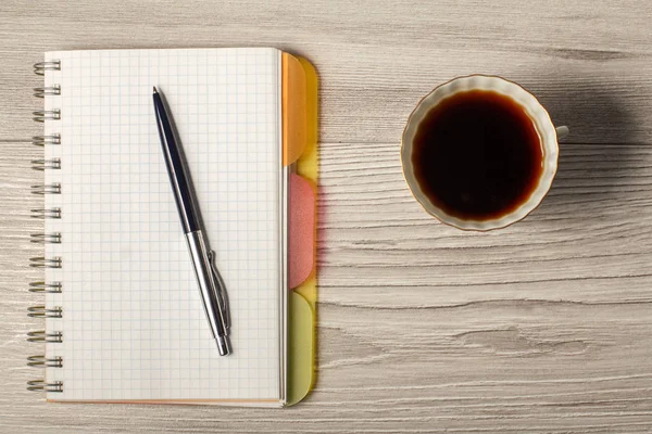 Σημειωματάριο, στυλό και φλυτζάνι καφέ σε γκρι φόντο ξύλινη — Φωτογραφία Αρχείου