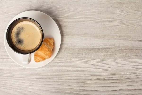 Vista superior da xícara de café preto com croissant fresco no pires w — Fotografia de Stock