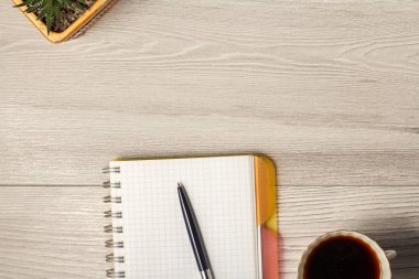 Defter, kalem, bardak kahve ve bir gri ahşap üzerinde bir tencerede bitki