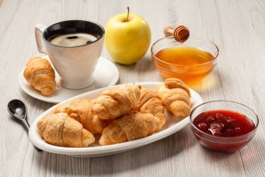 Uçan daire ile siyah kahve, beyaz porce üzerinde taze kruvasanlar fincan