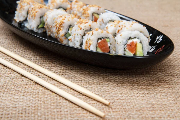 Uramaki rotoli di sushi con avocado e pesce rosso sul piatto di ceramica a — Foto Stock