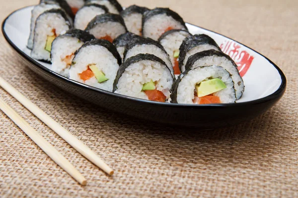 Rotoli di sushi in alghe nori con avocado e pesce rosso su ceramica — Foto Stock
