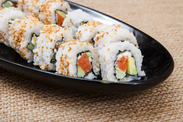 Rollos de sushi uramaki con aguacate y pescado rojo en plato de cerámica — Foto de Stock