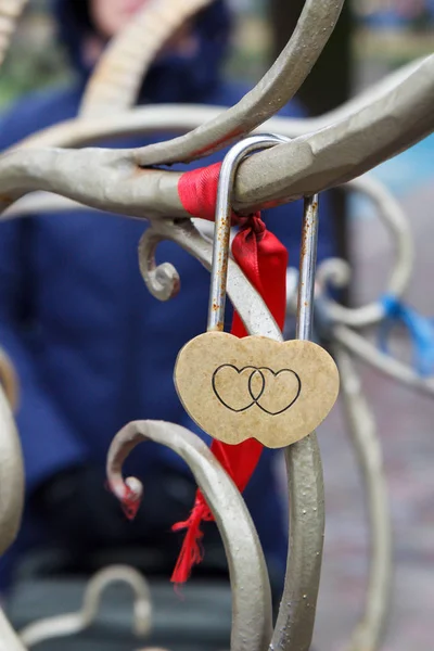 Padlock with engraving of two hearts on metal tree.