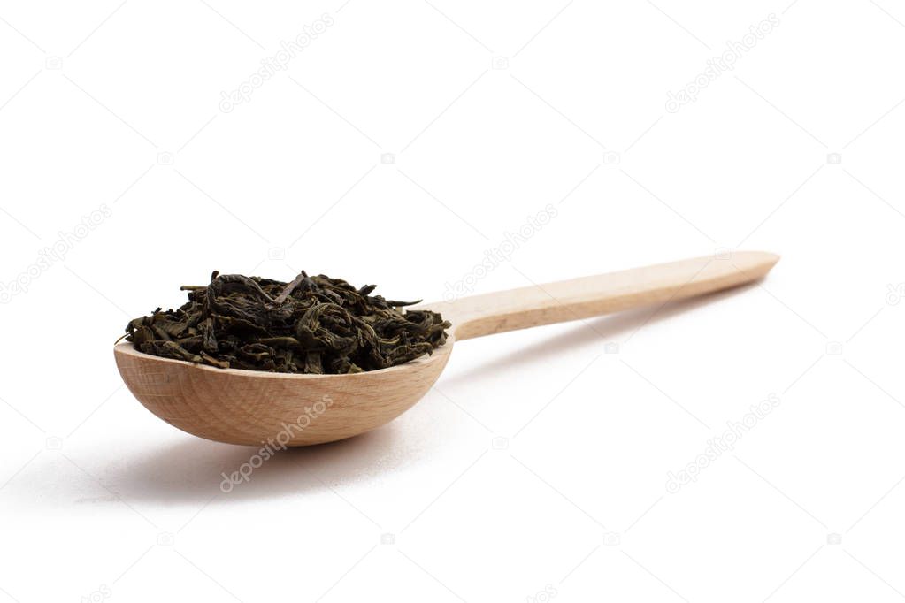 Wooden spoon with dry leaves of green tea with isolated backgrou