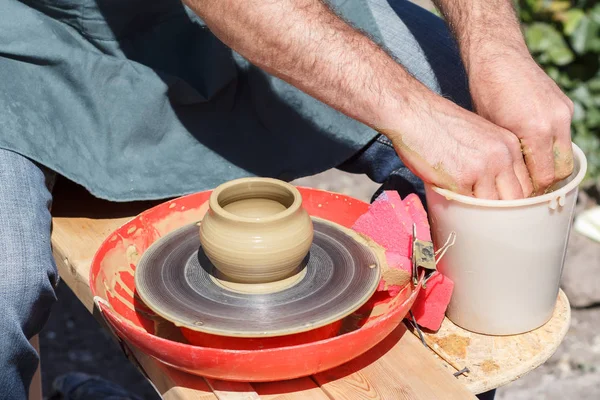 Creating clay jar by hands with potter wheel