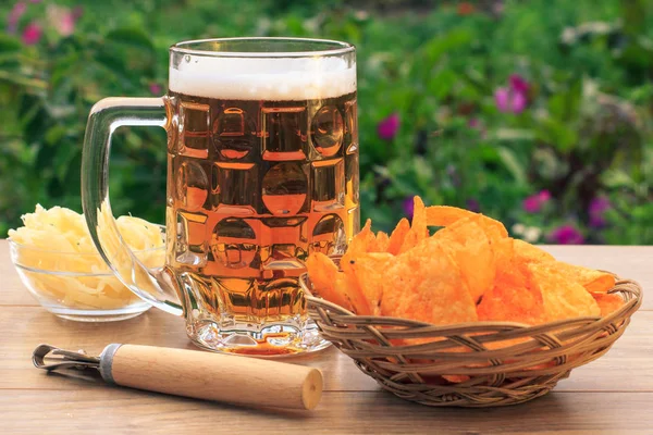 Tasse en verre de bière sur table en bois avec croustilles en osier ba — Photo
