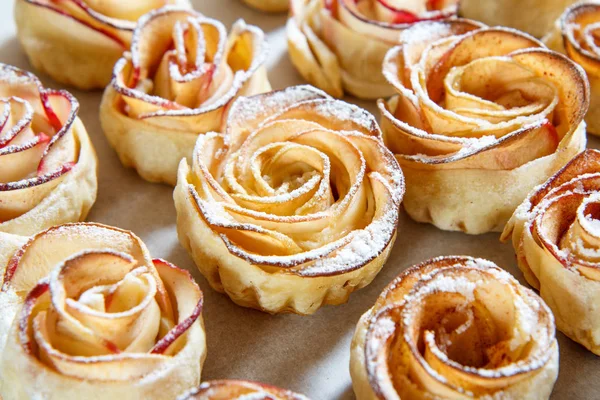 Galleta casera con manzanas en forma de rosa sobre papel de hornear — Foto de Stock