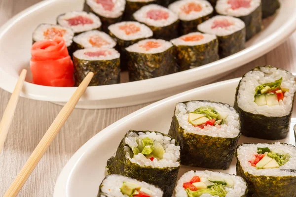 Rotoli di sushi con nori, riso, pezzi di avocado, cetriolo, rosso essere — Foto Stock