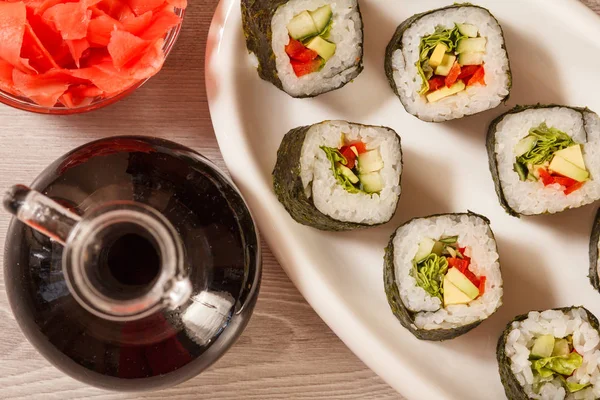 Rollos de sushi con arroz en plato de cerámica, botella de vidrio con sa de soja — Foto de Stock