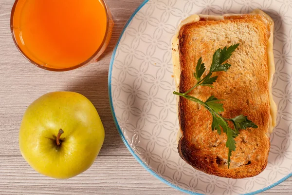 Toast with butter and cheese on white plate, apple and glass of — Stock Photo, Image