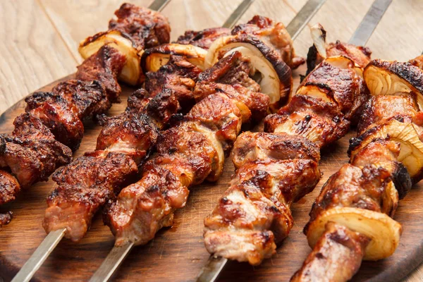Gegrild varkensvlees op een spies gebakken op de grill op houten hakken — Stockfoto