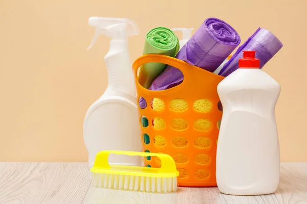 Botellas de líquido lavavajillas, cesta con bolsas de basura y esponjas en escritorio de madera . —  Fotos de Stock