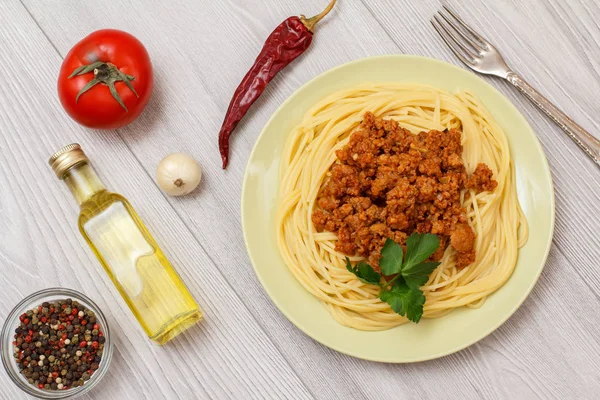 Placa con espaguetis boloñesa y verduras, especias para cocinar sobre tabla de madera . —  Fotos de Stock