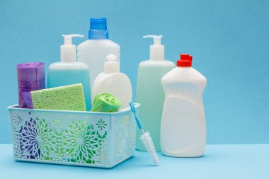 Mavi arka planda sepette bulaşık deterjanı şişeleri.