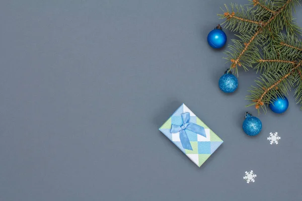 Confezione regalo, rami di abete con palline giocattolo, fiocchi di neve su sfondo grigio — Foto Stock