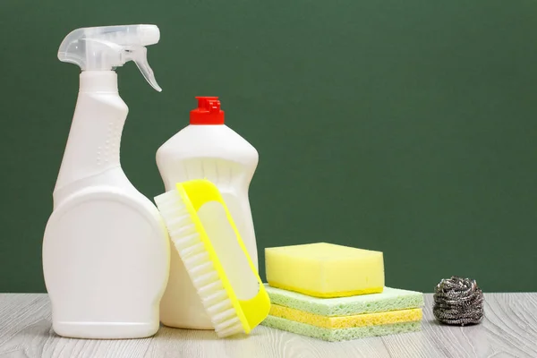 Bottles of glass cleaner, dishwashing liquid, brush and sponges on green background. — Stock Photo, Image