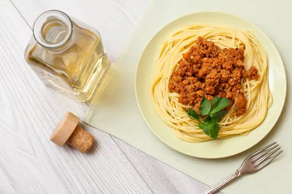 Espaguetis boloñeses en un plato con tenedor de metal y botella de vino . —  Fotos de Stock