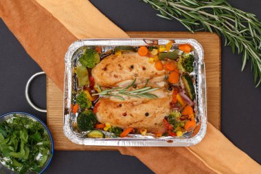 Fırında tavuk göğsü ya da metal kabın içinde sebze ve mutfak peçetesi olan fileto..