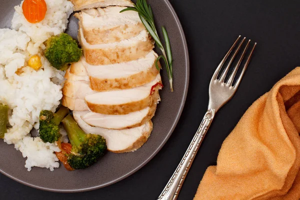 Baked chicken breasts or fillet on plate with rice and vegetables on plate.