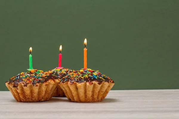 Születésnapi Cupcakes az égő ünnepi gyertyák, zöld háttér. — Stock Fotó
