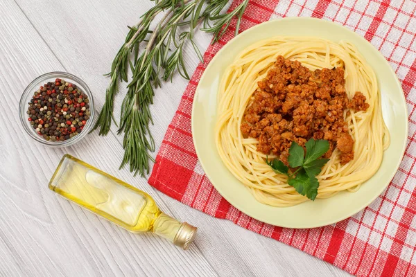 Espaguetis boloñesa en un plato, especias y hierbas con una servilleta . —  Fotos de Stock