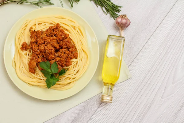 Placa con espaguetis boloñesa y verduras, condimentos para cocinar sobre tabla de madera . —  Fotos de Stock