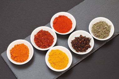 Taş kesme tahtasında çeşitli baharatlar ve otlar var..