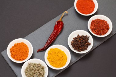 Taş kesme tahtasında çeşitli baharatlar ve otlar var..