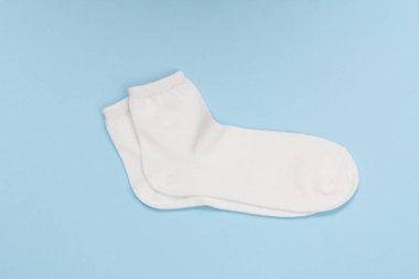 Mavi arka planda bir çift beyaz kadın çorabı.