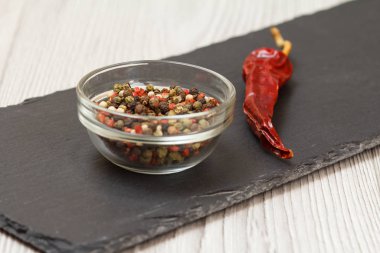 Kavanozda Allspice meyveleri ve taş kesme tahtasının üzerinde kırmızı biber..