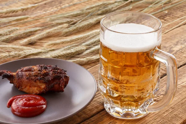 Verre de bière, assiette de poulet grillé et épis d'orge sur fond de bois . — Photo