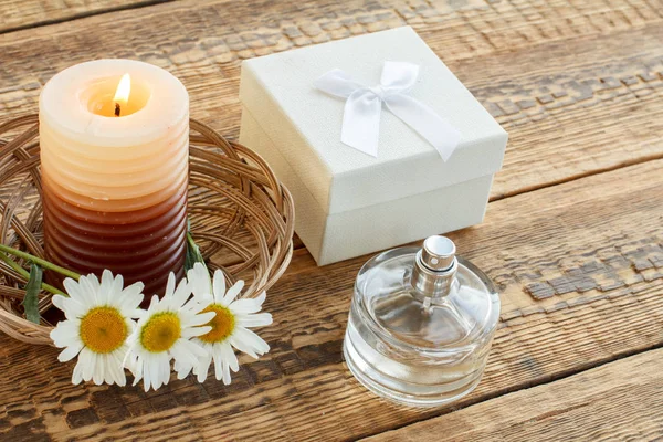 Perfume, vela, caixa de presente e flores frescas na mesa de madeira . — Fotografia de Stock