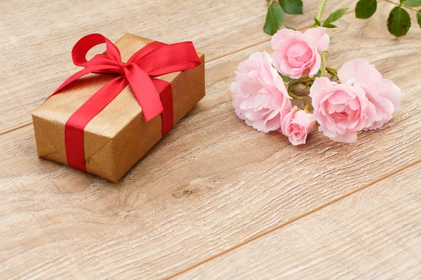 Caja de regalo con flores de color rosa sobre fondo de madera . — Foto de Stock