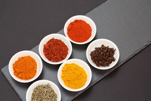 Various ground spices and herbs on stone cutting board. — Stock Photo, Image