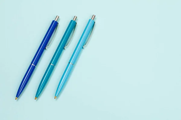 Três canetas de plástico sobre um fundo azul . — Fotografia de Stock