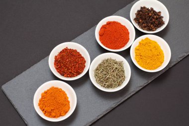 Taş kesme tahtasında çeşitli baharatlar ve otlar var..