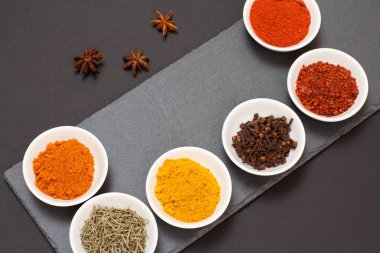 Taş kesme tahtasında çeşitli baharatlar ve otlar var..