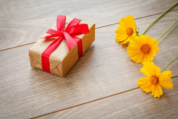 Geschenk doos op houten planken met bloemen — Stockfoto