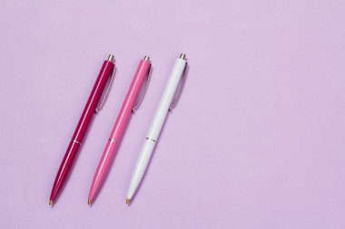 Eflatun arka planda üç plastik kalem.