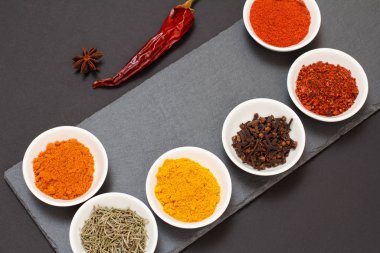 Taş kesme tahtasında çeşitli baharatlar ve otlar var..