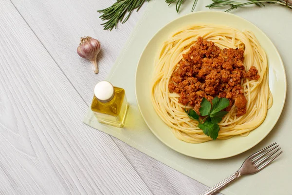 Placa con espaguetis boloñesa y verduras, condimentos para cocinar sobre tabla de madera . —  Fotos de Stock