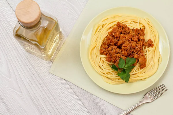 Espaguetis boloñeses en un plato con tenedor de metal y botella de vino . —  Fotos de Stock