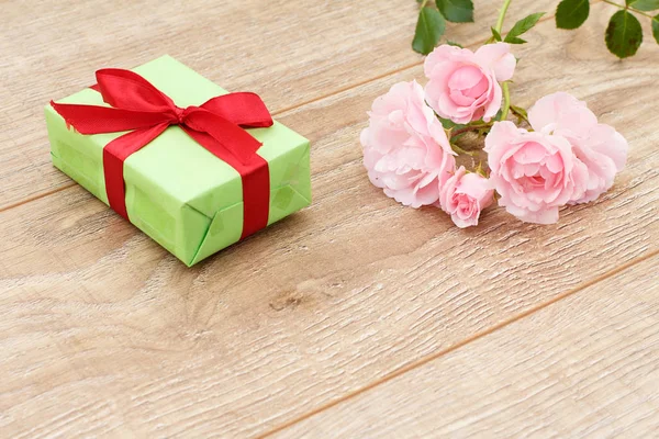 Подарункова коробка з квітами троянд на дерев'яному фоні . — стокове фото