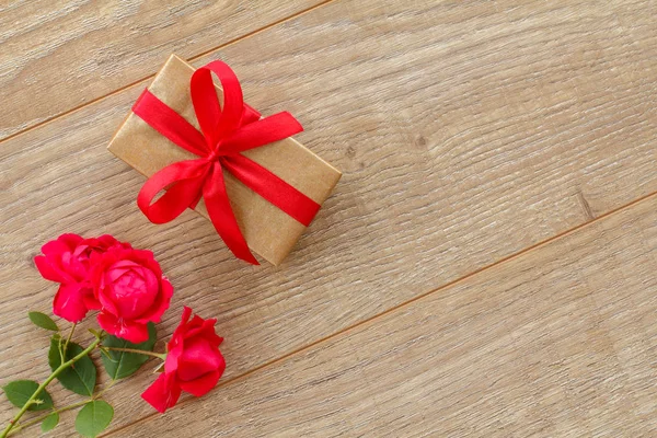 Gift box with flowers on the wooden background.
