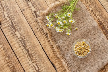 Kuru papatya çiçekli cam kase ve tahta tahtalarda taze olanlar..